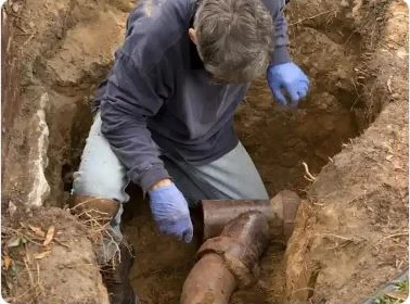 Technician repairing damaged underground sewer pipe